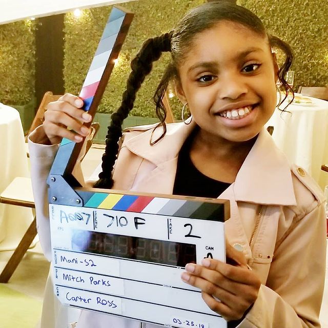 Brianni Walker in a black t-shirt and nude coat.